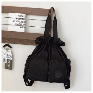 Detail of multi-functional black nylon drawstring bag with two front zipper pockets