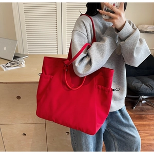 Detail of red canvas tote bag showing side drawstring pocket and durable fabric texture