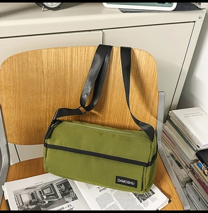 Gros plan sur un sac cylindrique en toile vert herbe avec sangles noires sur une chaise