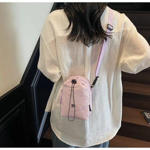 Vue arrière du modèle portant un petit sac bandoulière en nylon violet avec cordon de serrage
