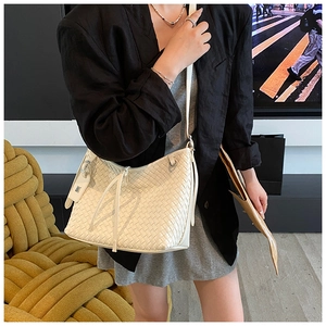 White woven crossbody bag styled on a model with a minimalist black blazer outfit