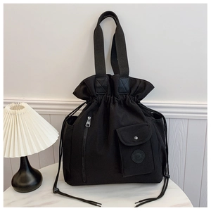 Close-up of black canvas bucket bag featuring drawstring closure and side metal buckle pocket