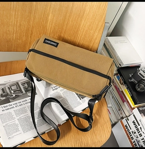 Sac bandoulière en toile kaki avec fermeture éclair noire et étiquette DAMOSHU