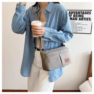 Detailed view of the gray multi-pocket canvas crossbody bag with adjustable wide strap