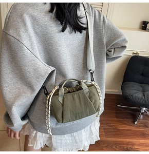 Detail of dark green canvas bucket bag featuring a drawstring closure and woven rope accents