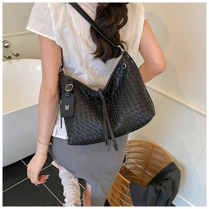 Detail of black woven hobo bag with grid pattern and adjustable strap with M tag