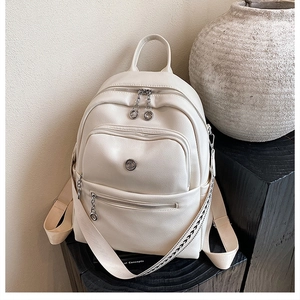 Detail of off-white leather backpack featuring silver ring zippers and woven strap accent