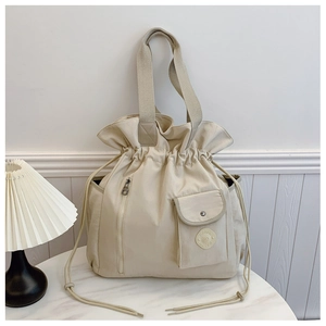 Detail of beige nylon tote bag with drawstring closure and functional front pockets