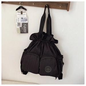 Detail of minimalist black nylon drawstring tote with functional dual zip pockets