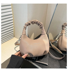 Détail d'un sac hobo plissé beige avec logo tendance et bandoulière amovible