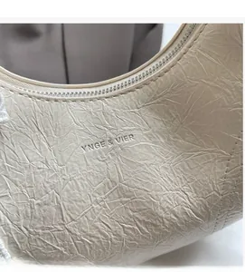 Detailed view of ivory pleated fabric and embossed logo on minimalist shoulder bag