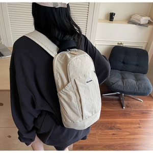 Close-up of cream textured nylon backpack with side pockets and woven brand label