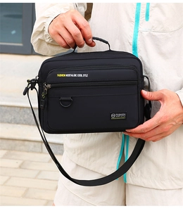 Detail of black oxford shoulder bag with adjustable strap and multiple zipper pockets