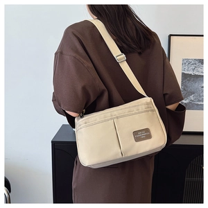 Detail of adjustable wide shoulder strap on a cream canvas crossbody messenger bag