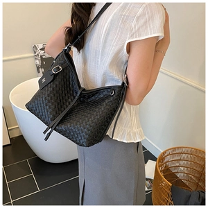 Detail of a black woven hobo shoulder bag with a silver buckle and letter M tag accessory