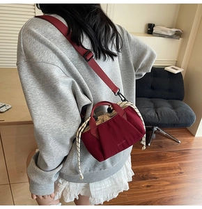Detailed shot of burgundy drawstring bucket bag with cream lining and brand logo