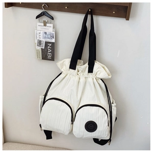 Detail of off-white pleated backpack featuring dual front zipper pockets and drawstring closure