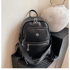 Detail view of black pebble leather backpack with decorative arrow pattern strap and zips