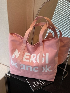 Pink canvas tote bag with white MERCI letter print for women shown in a modern interior