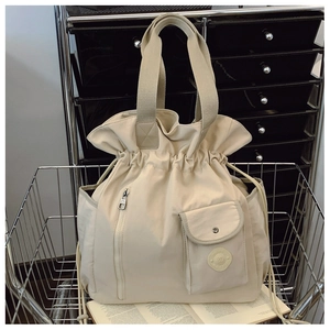 Detail of a beige pleated nylon bucket bag with zipper pocket in a metal basket