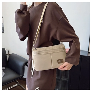 Detail of high-density beige nylon crossbody bag with multi-pocket design and strap