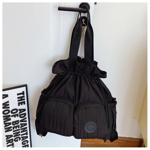 Macro detail of black nylon drawstring backpack with multiple functional zip pockets