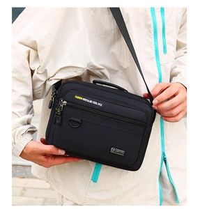Detail of multi-pocket black oxford crossbody bag with yellow printed lettering and D-ring