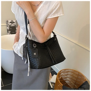 Detail shot of black woven hobo bag with adjustable leather strap and silver M charm