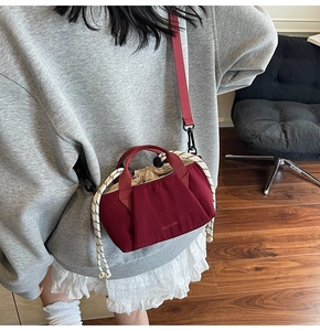 Deep red canvas bucket bag featuring a drawstring closure and logo detail on a model