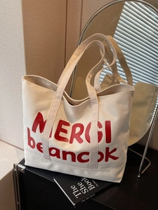 Minimalist canvas tote bag with red MERCI lettering and comfortable dual handles