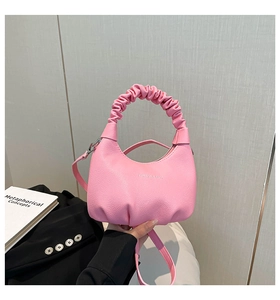 Détail d'un sac à main rose avec poignée plissée et texte gravé sur cuir grainé élégant