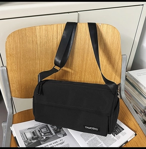 Détail du sac cylindre en toile noire avec étiquette DAMOSHU et sangle en nylon