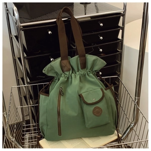 Detail of dark green canvas bucket bag with drawstring closure and front pocket