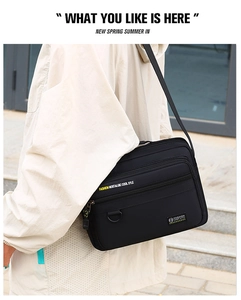 Detail of black oxford messenger bag with multiple zippers and adjustable shoulder strap