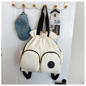 Close-up of cream nylon drawstring backpack with dual zip pockets and black strap details