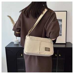 Detail of beige canvas crossbody bag showing functional pockets and adjustable strap