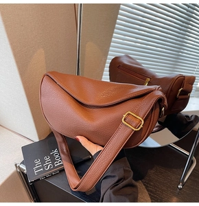 Detailed mirror view of brown textured leather crescent bag with gold buckle hardware