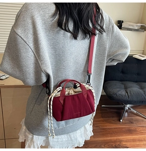 Detail of dark red canvas bucket bag featuring drawstring closure and woven rope handle