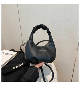 Détail du sac à main en cuir noir avec poignée plissée nuage et bandoulière amovible
