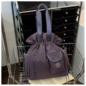Detail of purple nylon drawstring bucket bag with pockets in a metal shopping cart