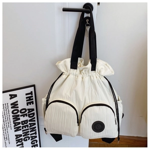 Detail of white pleated texture backpack featuring black drawstrings and dual front pockets