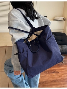 Large dark blue nylon tote bag with side drawstring and pockets for daily commuting