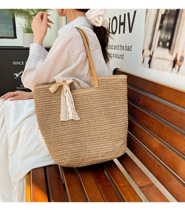 Detailed close-up of woven straw tote bag with elegant cream lace bow and leather straps