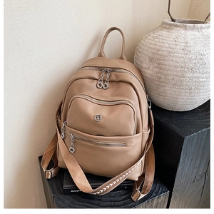 Detail of beige faux leather backpack with multiple zipper pockets and woven arrow strap