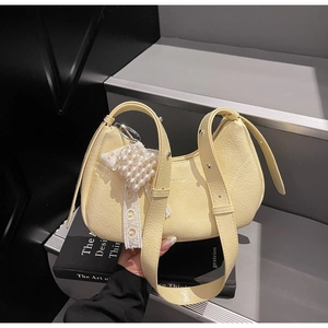 Detailed shot of yellow crescent bag with pearl lace charm and wrinkled leather texture