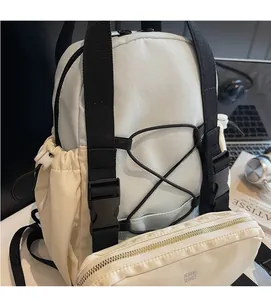 Detailed view of white contrast backpack featuring bungee cords and side drawstring pockets