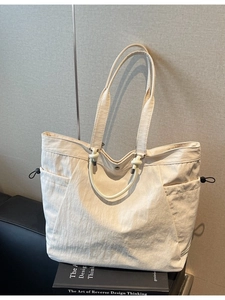 Minimalist cream canvas tote bag with dual straps and drawstring pockets for daily commute