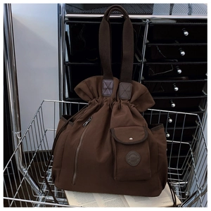 Detail of coffee brown pleated nylon tote bag with drawstring closure and front pocket