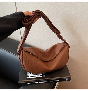 Detail of caramel crescent crossbody bag featuring lychee grain leather and gold hardware