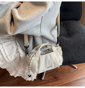 Detailed view of cream nylon bucket bag with drawstring closure and wide shoulder strap